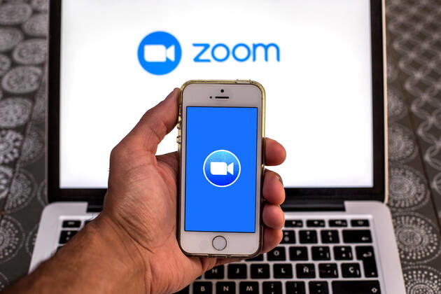 April 20, 2021, Barcelona, Catalonia, Spain: In this photo illustration, the Zoom app seen displayed on a smartphone screen and a Zoom logo on a laptop in the background. Barcelona Spain - ZUMAd159 20210420_zia_d159_093 Copyright: xThiagoxPrudenciox
