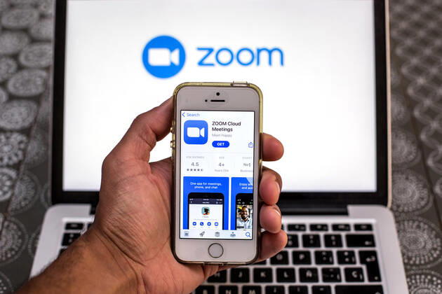 April 20, 2021, Barcelona, Catalonia, Spain: In this photo illustration, the Zoom app in App Store seen displayed on a smartphone screen and a Zoom logo on a laptop in the background. Barcelona Spain - ZUMAd159 20210420_zia_d159_094 Copyright: xThiagoxPrudenciox