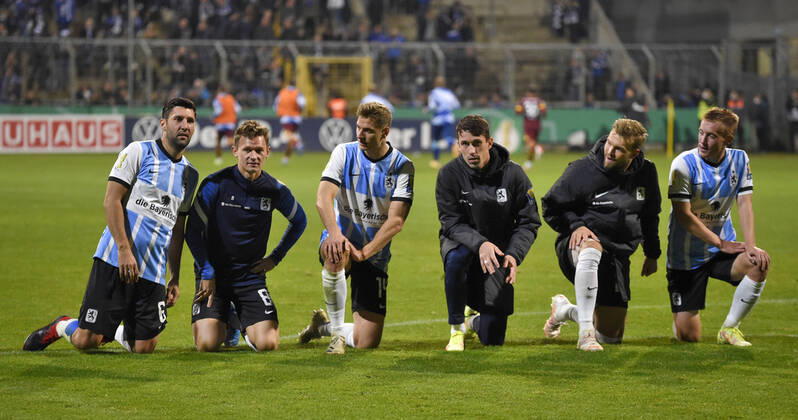 26.10.2021, Fussball DFB-Pokal 2021 2022, 2.Runde, TSV 1860 München - FC Schalke 04, im Grünwalder Stadion. v.l. Stephan Salger (1860 München), Erik Tallig (TSV 1860 München), Dennis Dressel (TSV 1860 München), Phillipp Steinhart (1860 München), Yannick Deichmann (TSV 1860 München) und Fabian Greilinger (TSV 1860 München) knieen vor den Fans