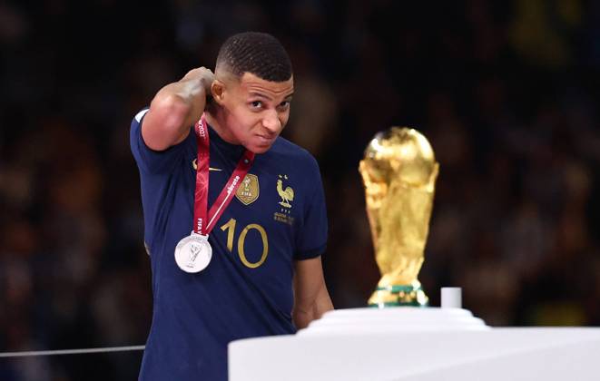 Doha, Qatar, 18th December 2022. Kylan Mbappe of France sneaks a lot athlete World Cup trophy as he collects his losers medal during the FIFA World Cup, WM, Weltmeisterschaft, Fussball 2022 match at Lusail Stadium, Doha. Picture credit should read: David Klein Sportimage EDITORIAL USE ONLY. No use with unauthorised audio, video, data, fixture lists, club league logos or live services. Online in-match use limited to 120 images, no video emulation. No use in betting, games or single club league player publications. SPI-2101-0232