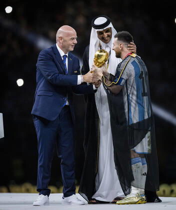 Doha, Qatar. 18th Dec, 2022. Lionel Messi of Argentina carries the FIFA World Cup, WM, Weltmeisterschaft, Fussball Qatar 2022 Winner s Trophy as Gianni Infantino, President of FIFA, and Sheikh Tamim bin Hamad Al Thani, Emir of Qatar, look on during the FIFA World Cup Qatar 2022 Final match between Argentina - France Final Match Argentinien - Frankreich World Cup 2022 in Qatar 18.12.2022