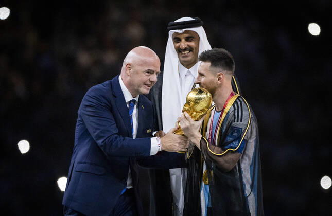 Doha, Qatar. 18th Dec, 2022. Lionel Messi of Argentina carries the FIFA World Cup, WM, Weltmeisterschaft, Fussball Qatar 2022 Winner s Trophy as Gianni Infantino, President of FIFA, and Sheikh Tamim bin Hamad Al Thani, Emir of Qatar, look on during the FIFA World Cup Qatar 2022 Final match between Argentina - France Final Match Argentinien - Frankreich World Cup 2022 in Qatar 18.12.2022