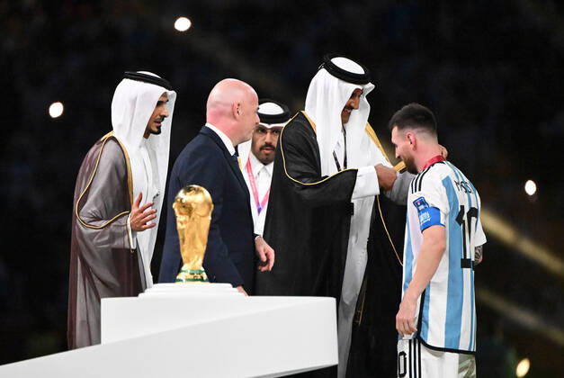 Fussball, Herren, Saison 2022 23, WM in Katar, Finale, Argentinien - Frankreich (2:2, 3:3 n. V, 4:2 i. E.) im Lusail Iconic Stadium in Lusail, v. l. FIFA-Präsident Gianni Infantino, Katars Emir Tamim bin Hamad Al Thani zieht Lionel Messi (Argentinien) bei der Siegerehrung ein Gewand an, 18.12. 2022, Copyright: xMatthiasxKochx