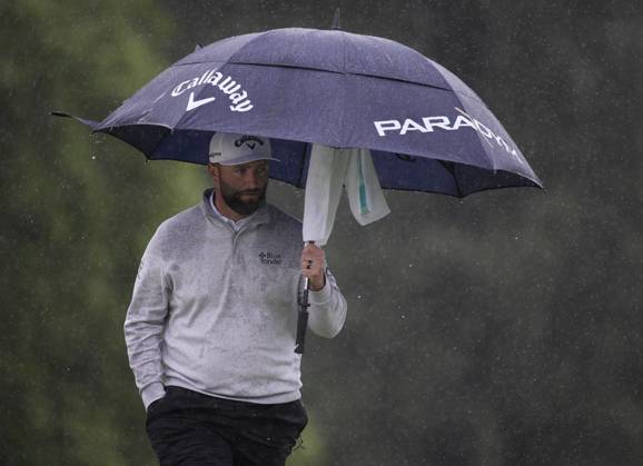 Jon Rahm protects himself from the rain at the 18th green during the rain delayed second round at the 87th Masters tournament at Augusta National Golf Club in Augusta, Georgia on Saturday, April 8, 2023. Rahm finished at 134 and in second place.  AUG20230408224 BOBxSTRONG
