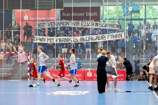 29.06.2025, 2. Handball Bundesliga, Nachholspiel, TuSEM Essen - Dessau-Rosslauer HV 06, Beim Einlauf der Mannschaften halten Fans aus Dessau ein Banner hoch mit der Aufschrift - Erst verhaun wir euch in scharen, dann mit Frank B. In Urlaub fahren, Protest an HBL Geschäftsführer Frank Bohmann, Essen Sporthalle Am Hallo NRW Deutschland xRHR-FOTO DEx Copyright: DennisxEwert RHR-FOTOx RHR-FOTO DE