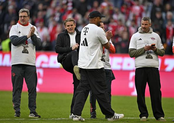19.04.2026, Fussball Bundesliga 2025 2026, 30.Spieltag, FC Bayern München - VfB Stuttgart, in der Allianz-Arena München, v.l. x, Sportdirektor Christoph Freund (Bayern München), x, Trainer Vincent Kompany (FC Bayern München) und x feiern mit Meister Kakadu T-Shirt. Sportdirektor Christoph Freund (Bayern München) gibt Trainer Vincent Kompany (FC Bayern München) einen Tritt
