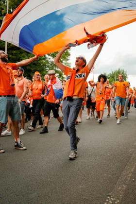 10.07.24, Football, UEFA EURO, EM, Europameisterschaft,Fussball 2024, Netherlands Fan March A Netherlands supporter raises his arms beneath a large orange, white and blue flag during the Dutch fan march in Dortmund, Germany, ahead of the UEFA Euro 2024 semi-final against England. Dortmund Dortmund NRW Germany