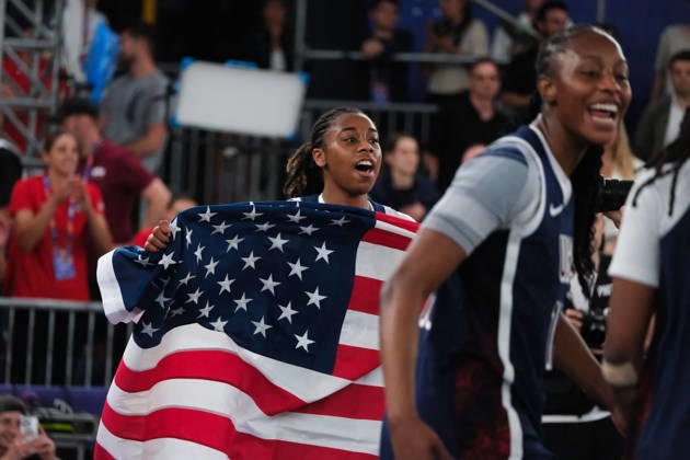 June 7, 2026, Warsaw, Masovian Voivodeship, Poland: USA s MIKAYLAH WILLIAMS (12) runs with an American flag towards her teammates in celebration of victory at the end of the FIBA 3x3 Basketball World Cup women s final game between Australia and USA in Warsaw, Poland. Team USA defeated Australia to become women s world champions. Warsaw Poland - ZUMAk204 20260607_zip_k204_026 Copyright: xRomanxKozielx