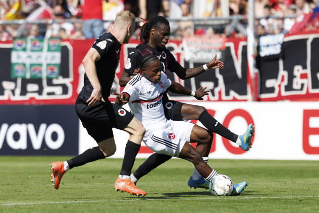 KOELN, GERMANY - AUGUST 22, 2026: Mohamed Alì Zoma (1. FC Nuernberg, 23) tackled by Meiko Sponsel (Viktoria Koeln, 19) and Yannick Tonye (Viktoria Koeln, 7) during the DFB-Cup match between Viktoria Koeln vs. 1. FC Nuernberg at the Sportpark Hoehenberg on August 22, 2026 in Koeln, Germany. DFL REGULATIONS PROHIBIT ANY USE OF PHOTOGRAPHS AS IMAGE SEQUENCES AND OR QUASI-VIDEO. Nordrhein-Westfalen Germany Copyright: xAxelxKohringx
