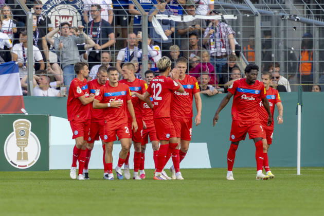 München, Deutschland 22. August 2026: DFB-Pokal - 2026 2027 - 1. Runde - TSV 1860 München gegen Holstein Kiel Im Bild: in der Traube Torschütze Phil Harres(Kiel) jubelt nach seinem Tor zum 0:1 mit seinen Mannschaftskollegen, DFB DFL regulations prohibit any use of photographs as image sequences and or quasi-video Grünwalder Stadion Bayern Copyright: xFotostandx xSchäferx