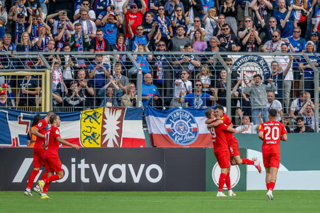 Die Kieler bejubeln vor der eigenen Fankurve mit Phil Harres (Holstein Kiel, 19) dessen Tor zum 0:1 GER, TSV 1860 Muenchen vs. Holstein Kiel, Fussball, DFB-Pokal, 1. Runde, Saison 2026 2027, 22.08.2026. (DFL DFB REGULATIONS PROHIBIT ANY USE OF PHOTOGRAPHS as IMAGE SEQUENCES and or QUASI-VIDEO). Foto: HMB Media Heike Feiner Copyright: HMBxMedia HeikexFeiner