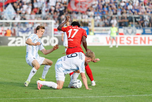Fabio Wagner (9, TSV 1860 München) und Faride Alidou (17, Holstein Kiel) beim Spiel zwischen TSV 1860 München v Holstein Kiel, Fussball, Herren, Dfb Pokal, 2026 2027, 1.Runde am 22.08.2026 in München, Städtisches Stadion an der Grünwalder Straße. Bayern Deutschland
