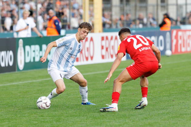 Emre Erdogan (19, TSV 1860 München) und Adrian Kapralik (20, Holstein Kiel) beim Spiel zwischen TSV 1860 München v Holstein Kiel, Fussball, Herren, Dfb Pokal, 2026 2027, 1.Runde am 22.08.2026 in München, Städtisches Stadion an der Grünwalder Straße. Bayern Deutschland