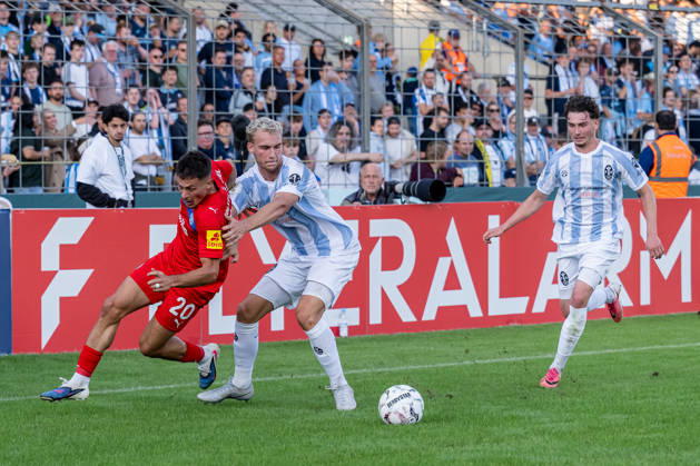 Kampf um den Ball Zweikampf zwischen Kampf um den Ball Zweikampf zwischen Lasse Fassmann (TSV 1860 Muenchen, 33) und Adrian Kapralik (Holstein Kiel, 20), dahinter Lance Fiedler (, TSV 1860 Muenchen, 47) GER, TSV 1860 Muenchen vs. Holstein Kiel, Fussball, DFB-Pokal, 1. Runde, Saison 2026 2027, 22.08.2026. (DFL DFB REGULATIONS PROHIBIT ANY USE OF PHOTOGRAPHS as IMAGE SEQUENCES and or QUASI-VIDEO). Foto: HMB Media Heike Feiner Copyright: HMBxMedia HeikexFeiner