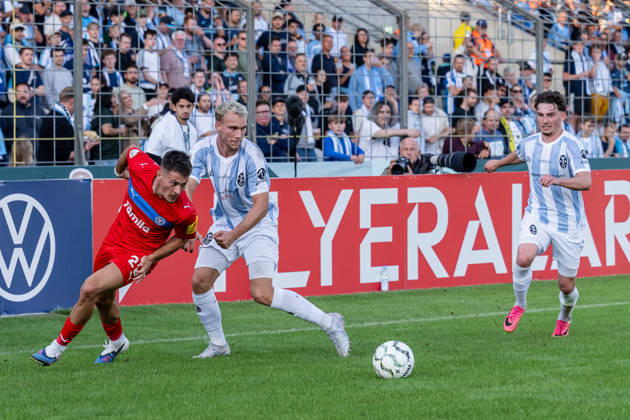 Kampf um den Ball Zweikampf zwischen Kampf um den Ball Zweikampf zwischen Lasse Fassmann (TSV 1860 Muenchen, 33) und Adrian Kapralik (Holstein Kiel, 20), dahinter Lance Fiedler (, TSV 1860 Muenchen, 47) GER, TSV 1860 Muenchen vs. Holstein Kiel, Fussball, DFB-Pokal, 1. Runde, Saison 2026 2027, 22.08.2026. (DFL DFB REGULATIONS PROHIBIT ANY USE OF PHOTOGRAPHS as IMAGE SEQUENCES and or QUASI-VIDEO). Foto: HMB Media Heike Feiner Copyright: HMBxMedia HeikexFeiner