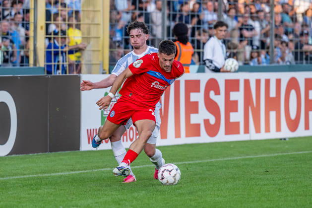 Kampf um den Ball Zweikampf zwischen Lance Fiedler (, TSV 1860 Muenchen, 47) und Adrian Kapralik (Holstein Kiel, 20) GER, TSV 1860 Muenchen vs. Holstein Kiel, Fussball, DFB-Pokal, 1. Runde, Saison 2026 2027, 22.08.2026. (DFL DFB REGULATIONS PROHIBIT ANY USE OF PHOTOGRAPHS as IMAGE SEQUENCES and or QUASI-VIDEO). Foto: HMB Media Heike Feiner Copyright: HMBxMedia HeikexFeiner