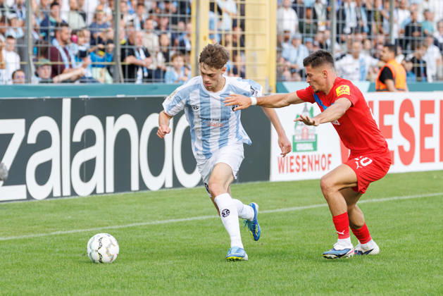 Emre Erdogan (19, TSV 1860 München) und Adrian Kapralik (20, Holstein Kiel) beim Spiel zwischen TSV 1860 München v Holstein Kiel, Fussball, Herren, Dfb Pokal, 2026 2027, 1.Runde am 22.08.2026 in München, Städtisches Stadion an der Grünwalder Straße. Bayern Deutschland