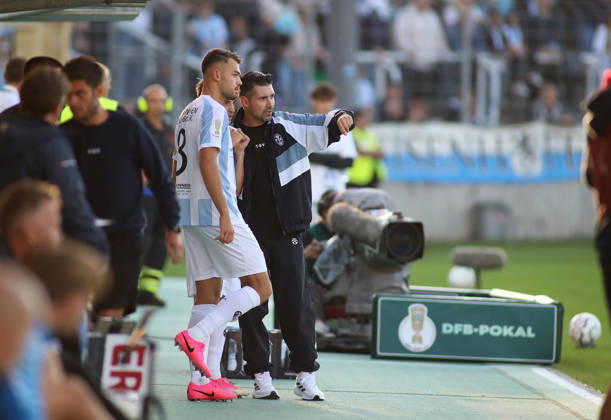 Fussball, Herren, DFB-Pokal, 1.Hauptrunde, Saison 2026 2027, TSV 1860 München - Holstein Kiel, Grünwalder Stadion Raphael Wach (TSV 1860 München) (li.) bekommt von Alper Kayabunar, Trainer (TSV 1860 München) (re.) letzte Anweisungen vor seiner Einwechslung