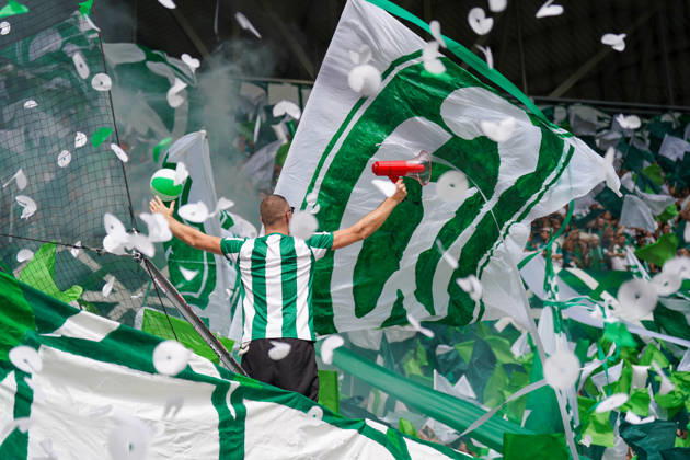 Deutschland: Fussball Bundesliga Saison 2026 - 2027, 1. Spieltag - SC Freiburg vs Werder Bremen - Europa Park Stadion (Freiburg): Fankurve von Werder Bremen im Stadion: Vorsänger mit Megafon vor dicht gedrängten Fans, umgeben von großen grün-weißen Schwenkfahnen. Grüner Rauch, Konfetti und Luftschlangen prägen die Choreographie. Zuschauer, Fans, Ultras, Supporter, Tribüne, Fanblock, Fankultur, Fanchoreo, Choreographie, Fahnenmeer, Megafon, Rauch, Pyrotechnik, Konfetti, Stimmung, Emotionen. Copyright: xJOERANxSTEINSIEKx