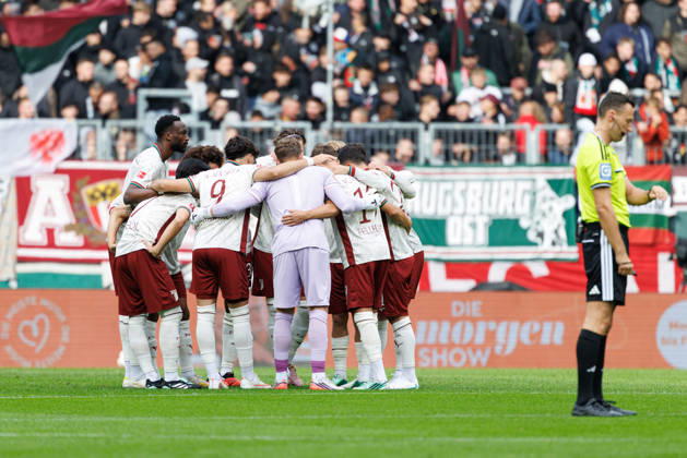 Team (FC Augsburg), Spielerkreis im Vordergrund, Sven Jablonski (Schiedsrichter:in) beim Spiel zwischen FC Augsburg v FC Bayern München, Fussball, Herren, Bundesliga, 2026 2027, 5.Spieltag am 10.10.2026 in Augsburg, WWK ARENA. DFL and DFB regulations prohibit any use of photographs as image sequences and or quasi-video. Bayern Deutschland