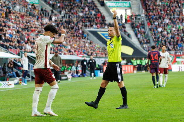 Sven Jablonski (Schiedsrichter:in) zeigt Rodrigo Ribeiro (9, FC Augsburg) die gelbe Karte beim Spiel zwischen FC Augsburg v FC Bayern München, Fussball, Herren, Bundesliga, 2026 2027, 5.Spieltag am 10.10.2026 in Augsburg, WWK ARENA. DFL and DFB regulations prohibit any use of photographs as image sequences and or quasi-video. Bayern Deutschland