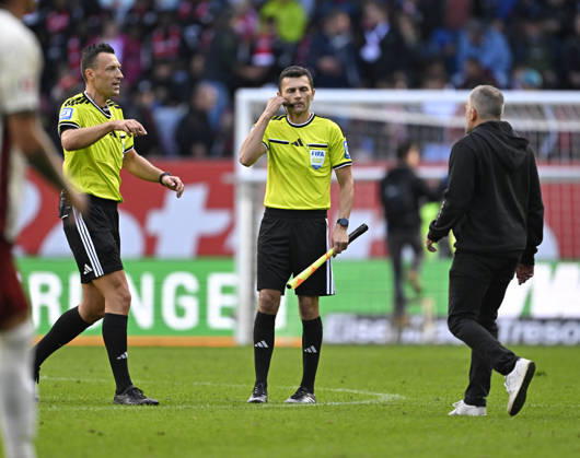 10.10.2026, Fussball Bundesliga 2026 2027, 5.Spieltag, FC Augsburg - FC Bayern München, in der WWK-Arena Augsburg, Trainer Manuel Baum (FC Augsburg) rennt in der Halbzeitpause zu Schiedsrichter Sven Jablonski (Deutschland)