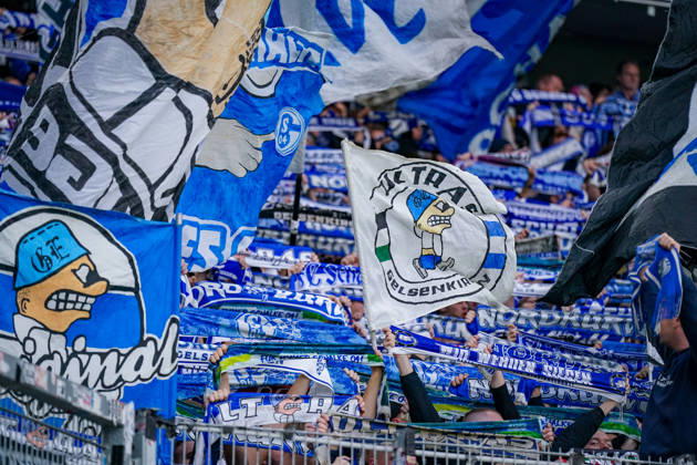 Deutschland: Fußball Bundesliga 2026 - 2027, 5. Spieltag - SC Freiburg - FC Schalke 04 - Europa-Park-Stadion (Freiburg): Detailaufnahme zahlreicher Fans des FC Schalke 04 im Gästeblock beim Auswärtsspiel gegen den SC Freiburg im Europa-Park Stadion. Blau-weisse Schwenkfahnen mit Motiven der Ultras Gelsenkirchen und hochgehaltene Fanschals. Schalke 04, S04, Königsblau, Ultras Gelsenkirchen, UGE, Ultras, Gästefans, Auswärtsfans, Fanszene, Fankultur, Fanblock, Gästeblock, Schalparade, Fahnenmeer, Fanflaggen, Schwenkfahnen, Fanartikel, Zuschauer, Tribüne, Bundesliga, Fussball, Stadion, Innenansicht. Copyright: xJOERANxSTEINSIEKx