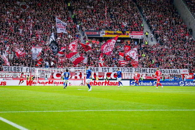 Deutschland: Fußball Bundesliga 2026 - 2027, 5. Spieltag - SC Freiburg - FC Schalke 04 - Europa-Park-Stadion (Freiburg): Totale der voll besetzten Heimtribüne des SC Freiburg beim Spiel gegen den FC Schalke 04 im Europa-Park Stadion. Fans zeigen Fahnen und ein Spruchband mit der Aufschrift SELBST FÜR ARBEITSLOSE SCHALKER IST SO 17:30 ZIEMLICH ASOZIAL. SC Freiburg, SCF, Schalke 04, S04, Fussball, Fankultur, Ultras, Zuschauer, Südtribüne, Transparent, Spruchband, Fanprotest, Anstosszeit, Spielansetzung, Arbeitslose, Provokation, Rivalität, Hintertorperspektive, Stadion, Innenansicht. Copyright: xJOERANxSTEINSIEKx