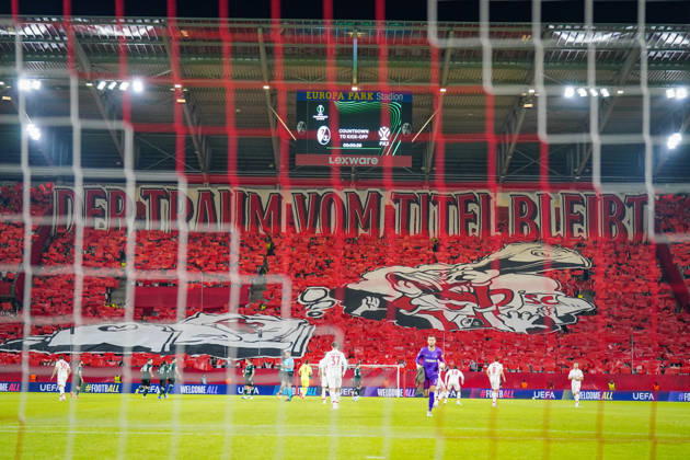 Deutschland: Fussball UEFA Conference League 2026 - 2027, 1. Spieltag - SC Freiburg vs FK Jablonec - Europa-Park-Stadion (Freiburg): Choreographie der Fans des SC Freiburg auf der Südtribüne im Europa-Park-Stadion beim UEFA Conference League-Spiel gegen FK Jablonec. Rote Fan-Choreo mit überdimensionalem Spruchband DER TRAUM VOM TITEL BLEIBT und grosser SC-Freiburg-Motivfahne. Aufnahme aus der Hintertorperspektive durch das Tornetz mit Spielern auf dem Rasen. SC Freiburg, FK Jablonec, Europapokal, Fankultur, Ultras, Fans, Zuschauer, Choreographie, Fanchoreo, Transparent, Stadion, Anzeigetafel, Lexware, Werbung. Copyright: xJOERANxSTEINSIEKx