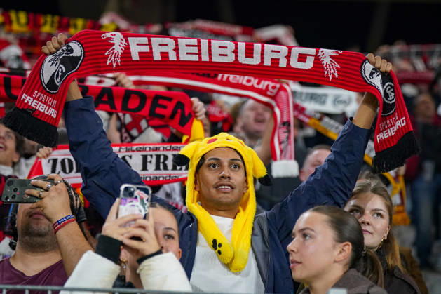 Deutschland: Fussball UEFA Conference League 2026 - 2027, 1. Spieltag - SC Freiburg vs FK Jablonec - Europa-Park-Stadion (Freiburg): Fan des SC Freiburg mit gelber Pikachu-Mütze hält einen rot-schwarzen Fanschal mit der Aufschrift FREIBURG und Vereinswappen über den Kopf. Porträt eines Anhängers auf der Tribüne des Europa-Park-Stadions beim UEFA Conference League-Spiel gegen FK Jablonec. SC Freiburg, Fussball, Europapokal, Fans, Zuschauer, Fankultur, Fanschal, Fanartikel, Merchandising, Pikachu, PokÃ mon, Kostüm, Verkleidung, Vereinsfarben, Heimfans, Stimmung, Begeisterung, Supporter, Smartphone, Stadion. Copyright: xJOERANxSTEINSIEKx
