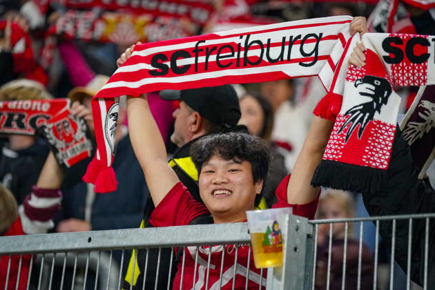 Deutschland: Fussball UEFA Conference League 2026 - 2027, 1. Spieltag - SC Freiburg vs FK Jablonec - Europa-Park-Stadion (Freiburg): Lächelnder Fan des SC Freiburg hält einen rot-weissen Fanschal mit der Aufschrift scfreiburg über den Kopf. Porträt eines begeisterten Anhängers auf der Tribüne des Europa-Park-Stadions beim UEFA Conference League-Spiel gegen FK Jablonec. SC Freiburg, FK Jablonec, Fussball, Europapokal, Fussballfan, Fans, Zuschauer, Fankultur, Fanschal, Vereinsfarben, Vereinswappen, Fanartikel, Merchandising, Emotionen, Begeisterung, Heimfans, Stadion, Tribüne, Supporter, Fanblock. Copyright: xJOERANxSTEINSIEKx