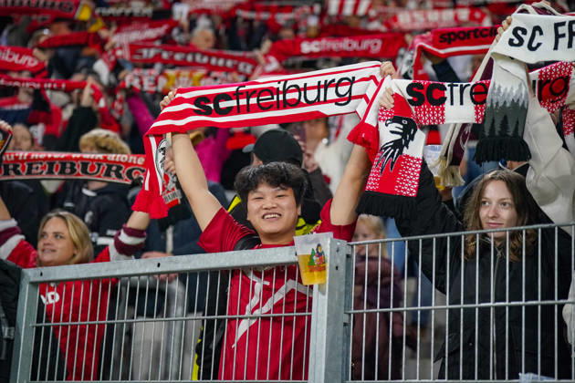 Deutschland: Fussball UEFA Conference League 2026 - 2027, 1. Spieltag - SC Freiburg vs FK Jablonec - Europa-Park-Stadion (Freiburg): Lächelnder Fan des SC Freiburg hält einen rot-weissen Fanschal mit der Aufschrift scfreiburg über den Kopf. Porträt eines begeisterten Anhängers auf der Tribüne des Europa-Park-Stadions beim UEFA Conference League-Spiel gegen FK Jablonec. SC Freiburg, FK Jablonec, Fussball, Europapokal, Fussballfan, Fans, Zuschauer, Fankultur, Fanschal, Vereinsfarben, Vereinswappen, Fanartikel, Merchandising, Emotionen, Begeisterung, Heimfans, Stadion, Tribüne, Supporter, Fanblock. Copyright: xJOERANxSTEINSIEKx