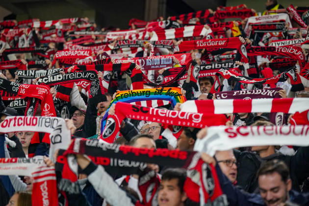 Deutschland: Fussball UEFA Conference League 2026 - 2027, 1. Spieltag - SC Freiburg vs FK Jablonec - Europa-Park-Stadion (Freiburg): Fans des SC Freiburg halten auf der Tribüne des Europa-Park-Stadions zahlreiche rot-weisse und schwarz-rote Fanschals in die Höhe. Geschlossenes Fanbild beim UEFA Conference League-Spiel gegen FK Jablonec. Sichtbar ist auch ein Regenbogenschal mit der Aufschrift Freiburg ist bunt. SC Freiburg, FK Jablonec, Fussball, Europapokal, Fans, Zuschauer, Fankultur, Fanblock, Fanschals, Vereinsfarben, Solidarität, Vielfalt, Diversität, Toleranz, LGBTQ, Stimmung, Heimfans, Supporter, Fanartikel, Stadion. Copyright: xJOERANxSTEINSIEKx