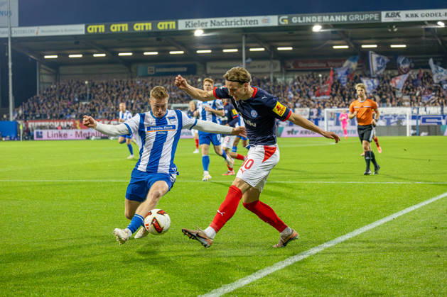 16.10.2026 Fußball 2. Bundesliga Männer Saison 2026 2027 8. Spieltag Holstein Kiel - Hertha BSC (Kiel in Dunkelblau, Berlin in Weiß Blau gestreift) Julian Eitschberger (li.), Jonas Therkelsen Kiel Holstein Stadion, Westring 501 Schleswig Holstein Deutschland