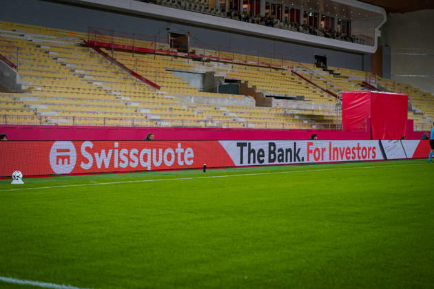 Fussball UEFA Conference League 2026 - 2027, 2. Spieltag - AS Monaco vs SC Freiburg - Stadion Louis II (Monaco): Blick auf die gesperrte Zuschauertribüne im Stade Louis II in Monaco während der Sanierungsarbeiten. Entfernte Sitzplätze, freigelegte Betonstufen und Bauabsperrungen unterhalb der VIP-Logen. Im Vordergrund LED-Werbebanden von Swissquote mit dem Slogan The Bank. For Investors. Stadionumbau, Tribünensanierung, Baustelle, Renovierung, Sportstätte, Innenansicht, Fussballstadion, Sponsoring, Banken, Finanzwirtschaft, Werbung, Werbebande, Wirtschaft. Copyright: xJOERANxSTEINSIEKx