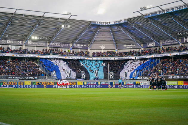 Deutschland: Fussball Bundesliga 2026 - 2027, 7. Spieltag - SC Paderborn vs Hamburger SV - Home-Deluxe-Arena (Paderborn): Innenansicht der Home-Deluxe-Arena in Paderborn mit grosser blau-schwarz-weisser Choreographie der Heimfans des SC Paderborn 07, Schriftzug HAMBURG. Fans, Ultras, Fanchoreo, Fanszene, Fahnen, Zuschauer, Tribüne, Fanblock, Stimmung, Mannschaftskreise von SC Paderborn und Hamburger SV vor Spielbeginn, Fussball, Bundesliga, Stadion, Sportstätte, Totale, Spielfeld, Schiedsrichter, Flutlicht, Werbung, Sponsoren, Werbebanden, Merkur, buXtrade, Varnholt, Welcome Hotel. Copyright: xJOERANxSTEINSIEKx