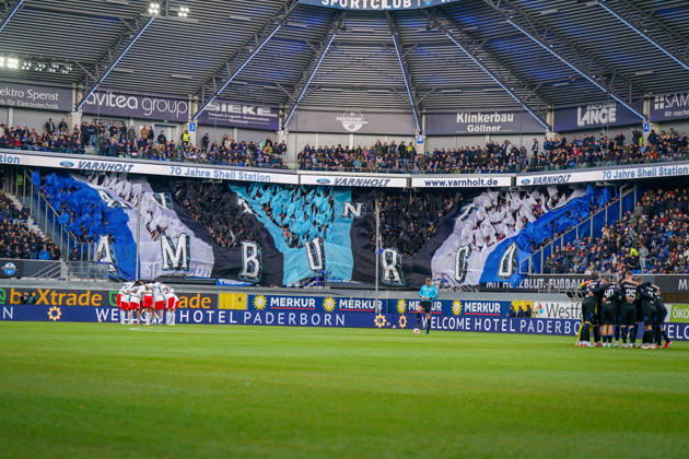 Deutschland: Fussball Bundesliga 2026 - 2027, 7. Spieltag - SC Paderborn vs Hamburger SV - Home-Deluxe-Arena (Paderborn): Innenansicht der Home-Deluxe-Arena in Paderborn mit grosser blau-schwarz-weisser Choreographie der Heimfans des SC Paderborn 07, Schriftzug HAMBURG. Fans, Ultras, Fanchoreo, Fanszene, Fahnen, Zuschauer, Tribüne, Fanblock, Stimmung, Mannschaftskreise von SC Paderborn und Hamburger SV vor Spielbeginn, Fussball, Bundesliga, Stadion, Sportstätte, Totale, Spielfeld, Schiedsrichter, Flutlicht, Werbung, Sponsoren, Werbebanden, Merkur, buXtrade, Varnholt, Welcome Hotel. Copyright: xJOERANxSTEINSIEKx
