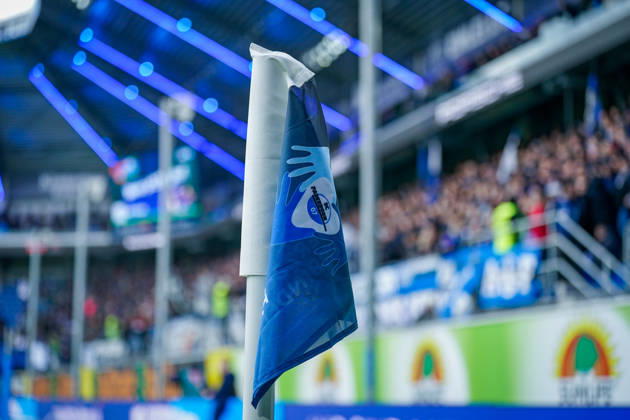 Deutschland: Fussball Bundesliga 2026 - 2027, 7. Spieltag - SC Paderborn vs Hamburger SV - Home-Deluxe-Arena (Paderborn): Detailaufnahme einer blau-weissen Eckfahne mit Vereinswappen des SC Paderborn 07 in der Home-Deluxe-Arena. Fussball, Bundesliga, SC Paderborn gegen Hamburger SV, HSV, Eckball, Eckstoss, Spielfeld, Spielfeldbegrenzung, Spielausrüstung, Equipment, Vereinslogo, Vereinsfarben, Heimspiel, Sportstätte, Stadion, Innenansicht, Nahaufnahme, selektive Schärfe, Zuschauer, Fans, Tribüne, Stadiondach, Flutlicht, LED-Beleuchtung, Werbung, Werbebanden. Copyright: xJOERANxSTEINSIEKx