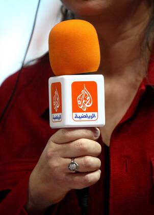 Journalistin mit einem Mikrofon des arabischen Nachrichtensenders Al Jazeera