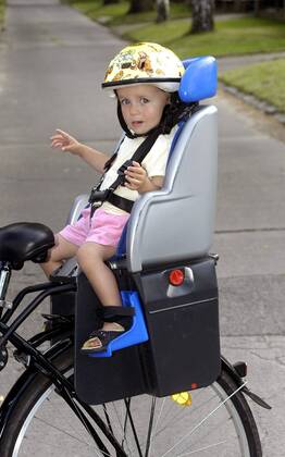 Kleines Mädchen sitzt mit Sturzhelm auf einem Kettler-Fahrradsitz