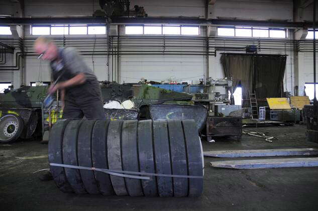 Mitarbeiter mit Bauteilen eines zerlegten Panzers in der Battle Tank Dismantling
