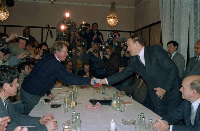 Playwrite and the representative of Civic Forum Vaclav Havel (L) shakes hands with Secretary of the government Marian Calfa. Other politicians, actors and the singer Michael Kocab are looking on in Prague, Czechoslovakia on Nov. 26, 1989. 
