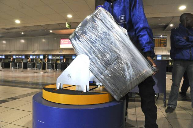 Baggage wrapped at airport to help prevent baggage theft - JOHANNESBURG, SOUTH AFRICA ? AUGUST 17: Baggage is wrapped at the OR Tambo International Airport on August 17, 2011 in Johannesburg, South Africa due to baggage theft. The situation which is getting out of control is prompting travellers to use alternatives to South African Airways. Gallo0000145030