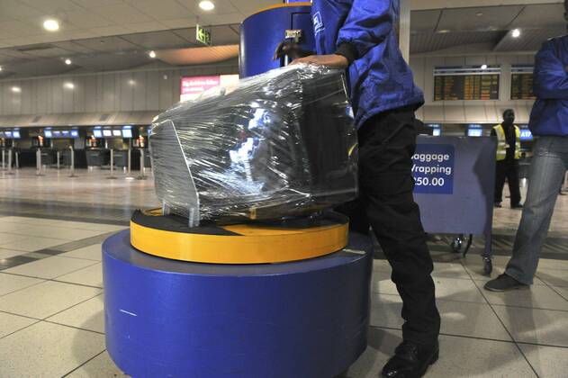 Baggage wrapped at airport to help prevent baggage theft - JOHANNESBURG, SOUTH AFRICA ? AUGUST 17: Baggage is wrapped at the OR Tambo International Airport on August 17, 2011 in Johannesburg, South Africa due to baggage theft. The situation which is getting out of control is prompting travellers to use alternatives to South African Airways. Gallo0000145033