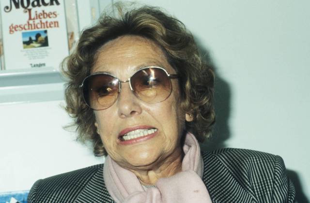 Barbara Noack (Autorin) 10 84 hör Autor Frau Literatur Buch Schriftstellerei Locken weißhaarig leger Blazer Schal Pullover sitzend Brille Titel Schild Ein Stück vom Leben Regal Bücherregal sprechend Portrait quer