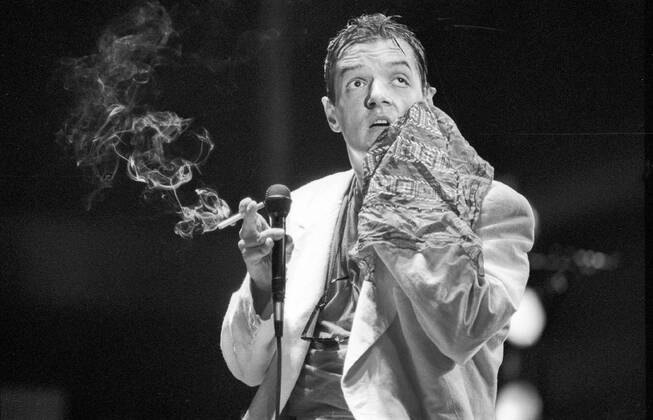 Falco (Sänger, Musiker) 10 86 dar Falco bei einem Konzert im Oktober 1986 Mann Gesang Musik Pop Rock Künstler Österreicher Österreich österreichisch österreichischer Johann Hölzel Bühne Auftritt Show seriös Hemd Jackett Sakko geschafft kaputt schwitzend Handtuch haltend Gesicht abwischend Mikro Mikrofon Zigarette dunkelhaarig Gelfrisur zurückgekämmt halb Singer Music Musician Performance Stage quer sw
