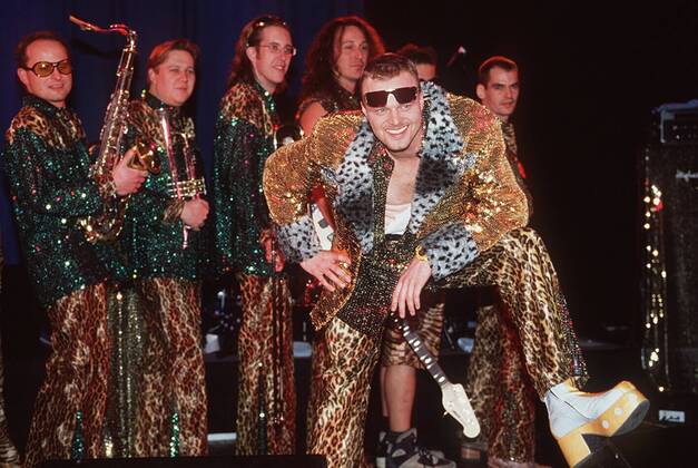 Stefan Raab und Band 11 97 her Mann TV Moderation Musik VIVA Unterhaltung dunkelhaarig Sonnenbrille leger Plateauschuh Leopardenhose quer ganz stehend Instrument neutral Bühne