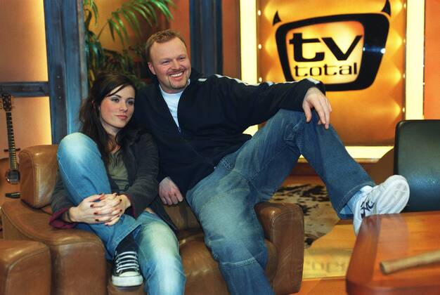 Stefan Raab mit Nora Tschirner in tv total (ProSieben) 01 03 pp Mann Moderator TV Fernsehen Moderation Musiker Musik Pop Gesang Sänger Produktion Unterhaltung Show dunkelhaarig kurzhaarig leger Trainingsjacke Sportjacke Shirt sitzend TV-Studio Kulisse Dekoration Logo halb quer sitzend lächelnd Sessel Fototermin tv total (ProSieben) am 06.01.2003 in Köln
