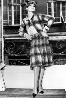 IMAGO ICONS: Coco Chanel Autumn Winter season from Coco Chanel . Chanel s winter suits featured many vivid colour combinations . This model shows her new pelated skirt topped by a slender straight jacket is in a blanket plaid in a vivid salmon and green combination , worn with a pink silk blouse . 29th July 1964  UnitedArchives01230264