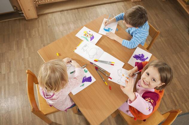 Germany, Children in nursery sitting at table drawing pictures, elevated view model released property released  RNF00221